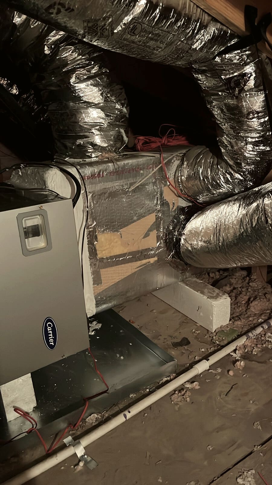 An attic air handler with a plenum and duct above it.