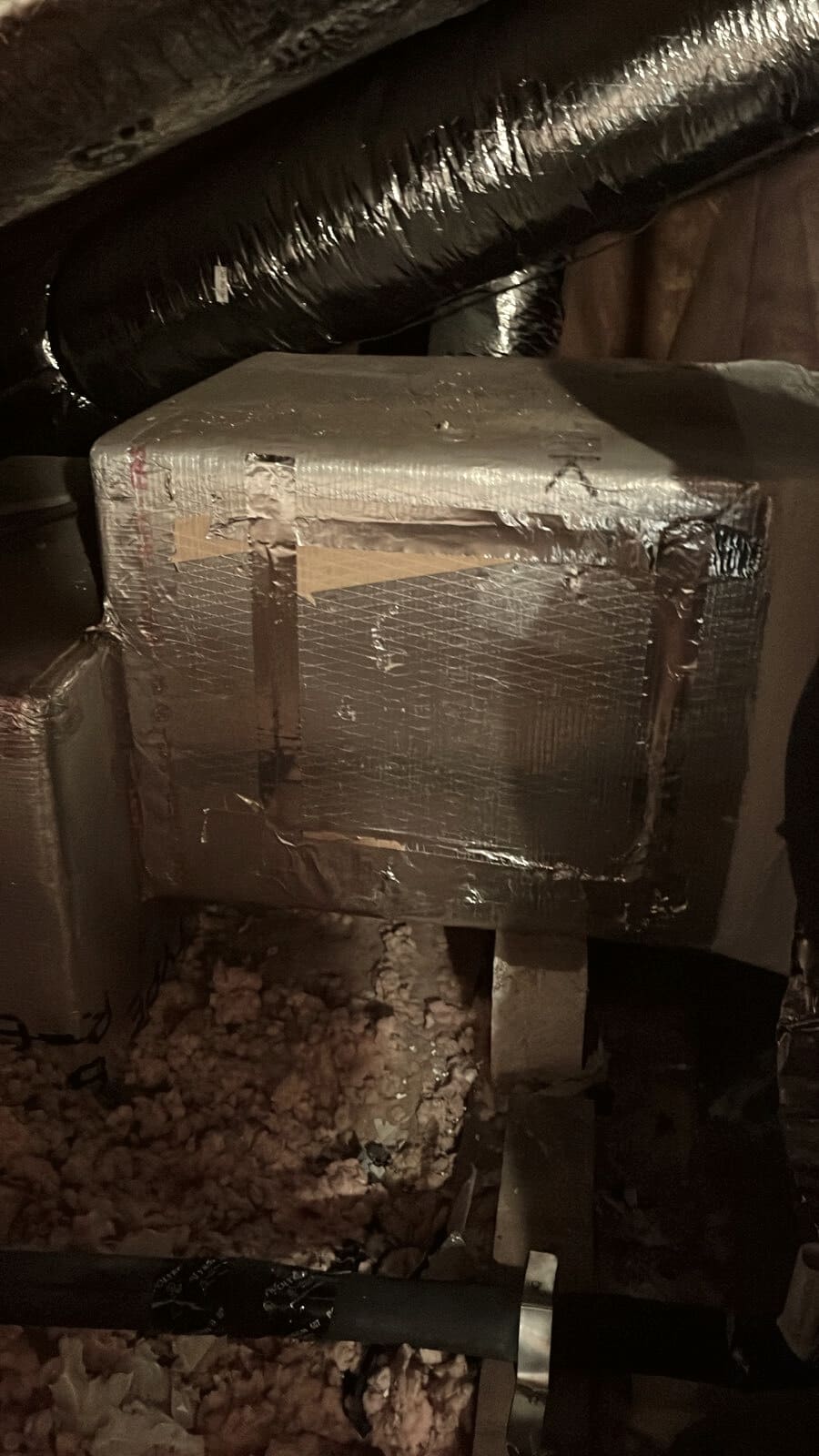 A plenum box in an attic with duct running over it.