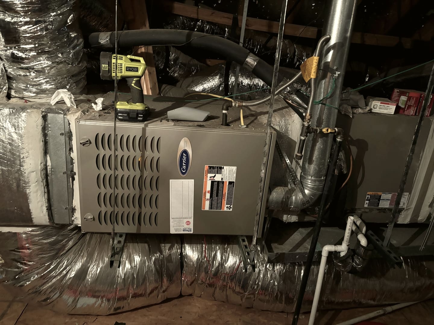 An air handler in an attic with flexible duct running out of it.