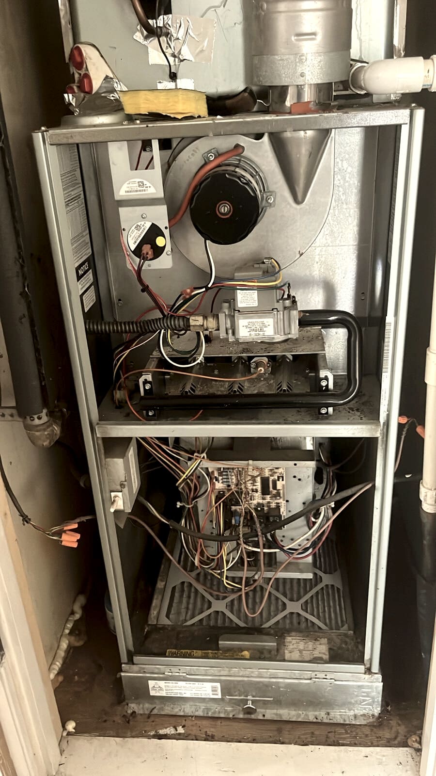 A furnace in a hallway closet with the door panels open.