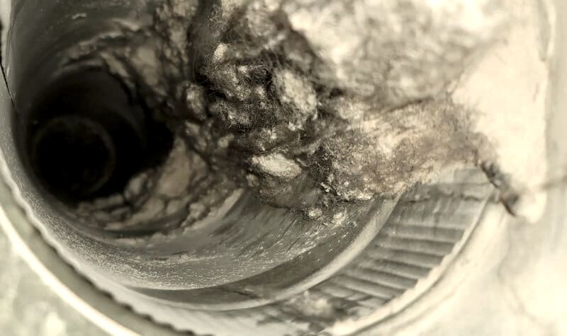Dark buildup inside a duct before cleaning.