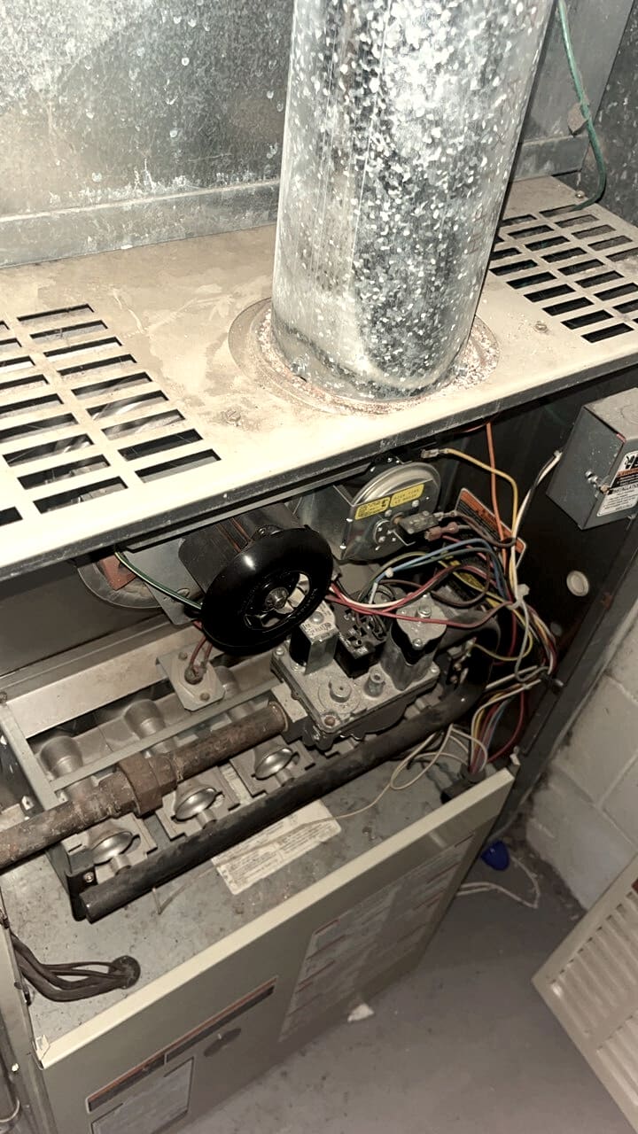 A furnace with the panel off, the burners and wiring in view.