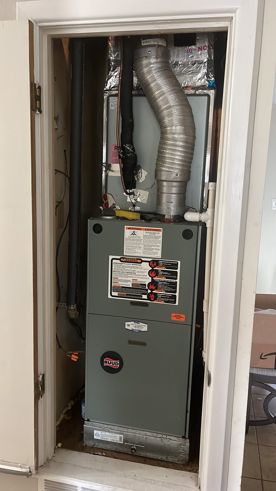 A new furnace installed in the same hallway closet, panels on and the flue connected.